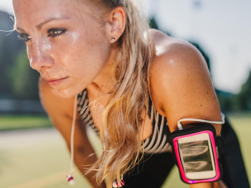 Sweaty, blond-haired woman resting after a hard workout on a sports field.