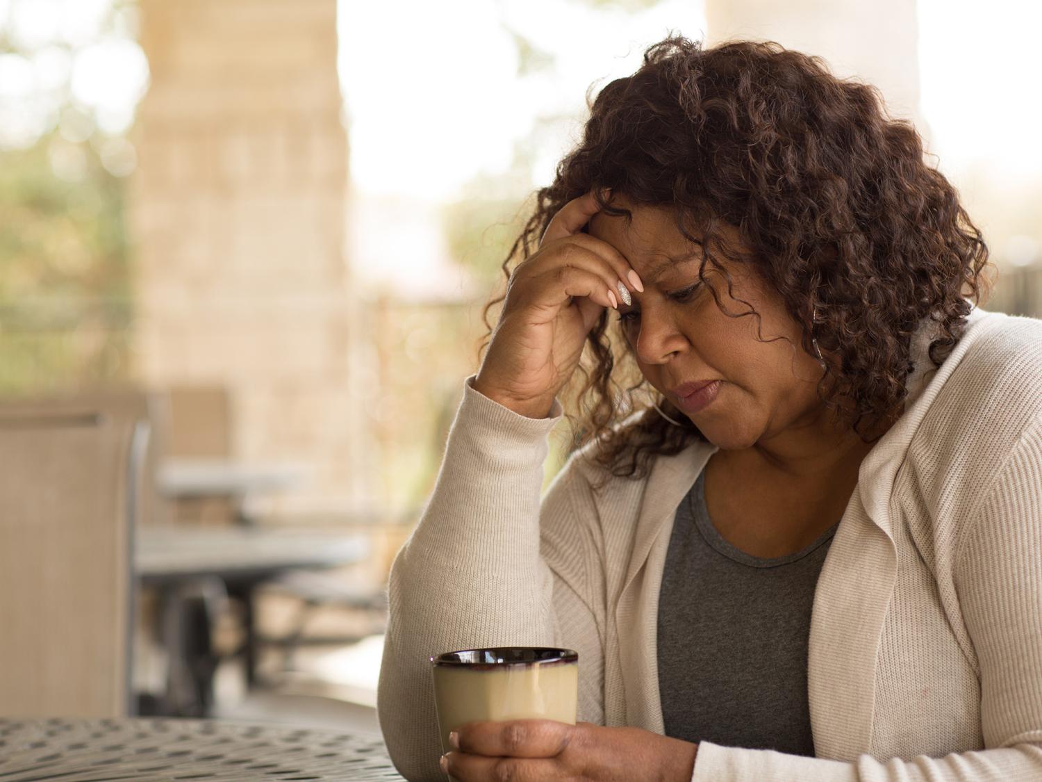 A person holding a mug looks worried.