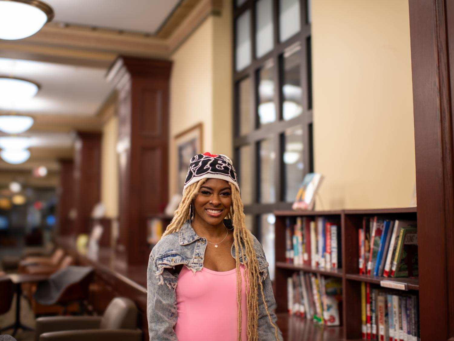 Alana Nesmith stands in the Pattee Library next to a wall of bookshelves.