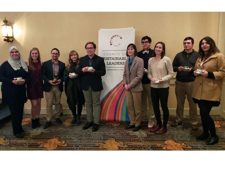 A group of people who have received an award next to a Council of Sustainable Leaders banner.