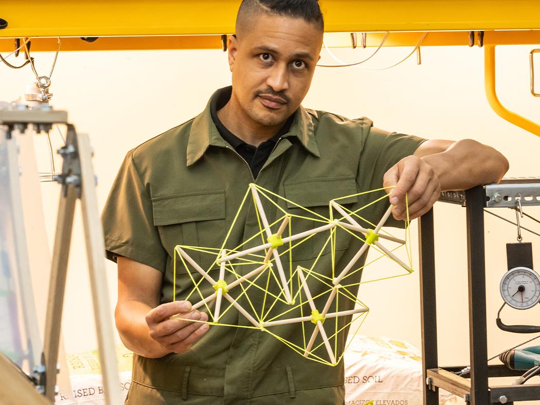 DK Osseo-Asare holding a model of a bamboo structure in his lab.