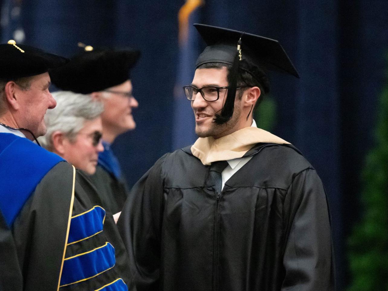 A graduate smiles at a faculty member during Penn State Behrend's commencement program.