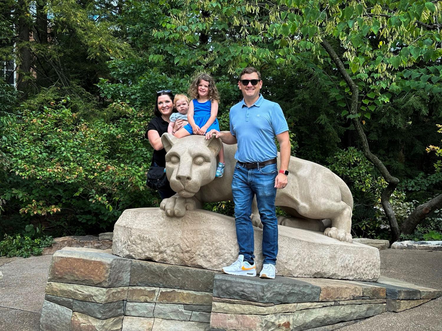 family of four poses on statue of lion