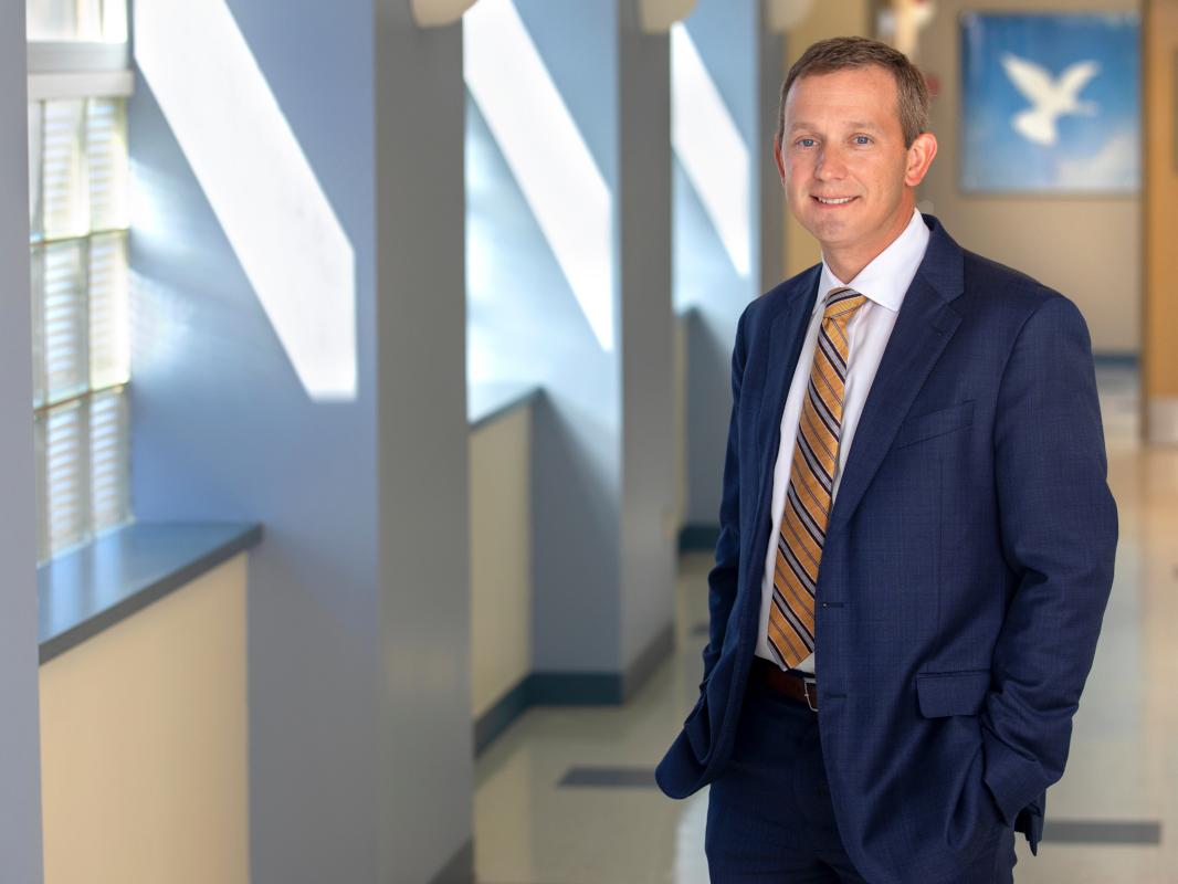 A man in a suit smiles for a portrait
