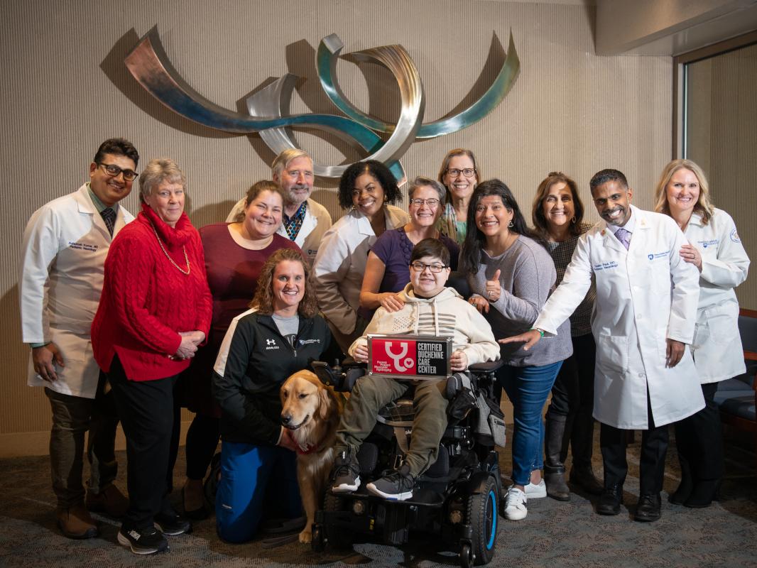A pediatric muscular dystrophy care team poses with a patient and their family for a photo
