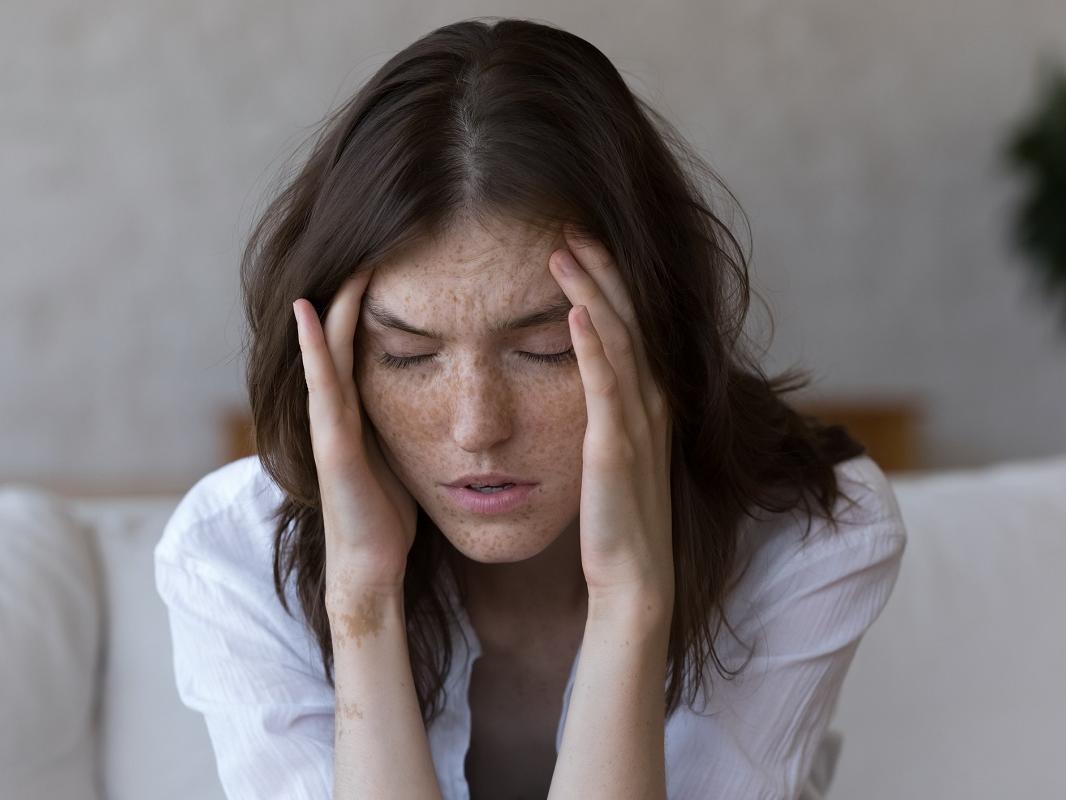 A woman touches the temples of her aching head.