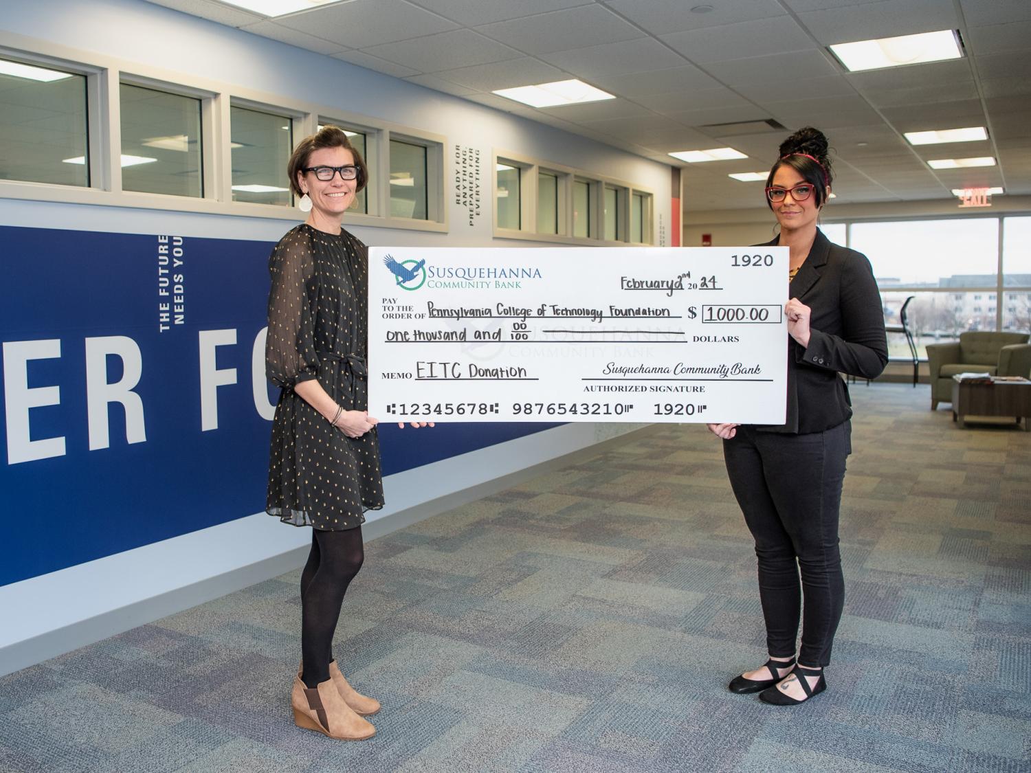 Two people hold up a huge check between them
