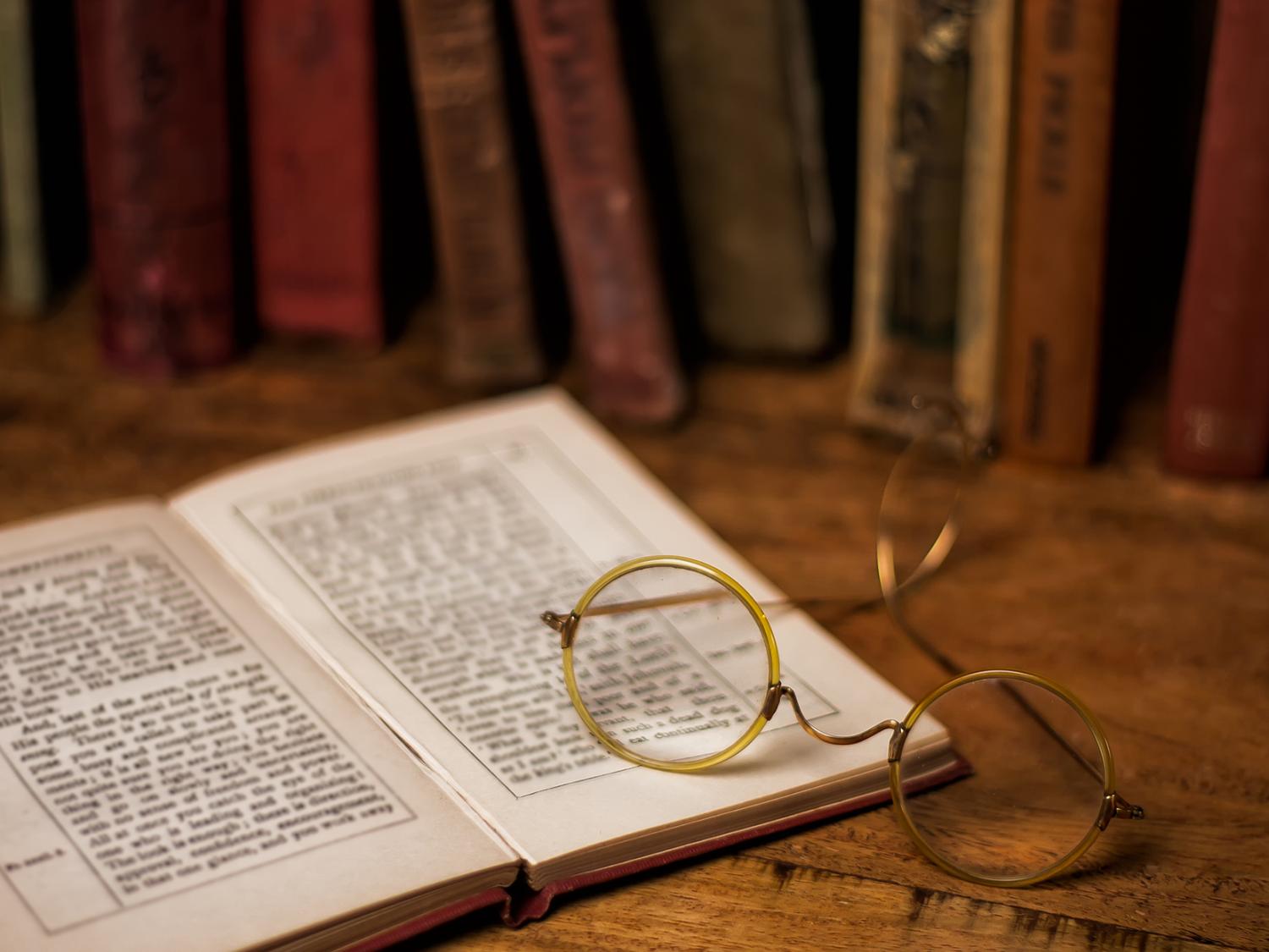 cirlcle frame eye glasses sitting atop an open book