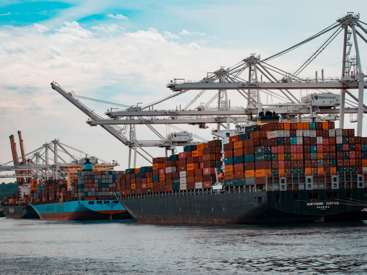 Cargo ships docked at a pier during the day. 