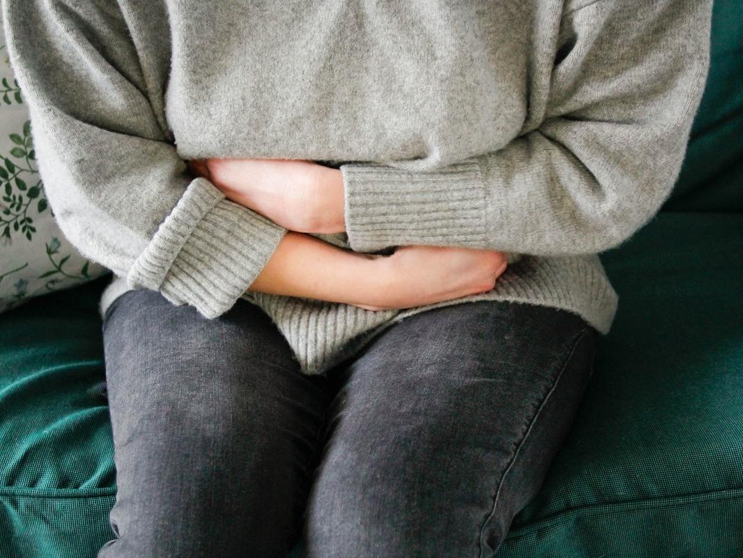Close-up of a woman clutching her midsection due to apparent pain.
