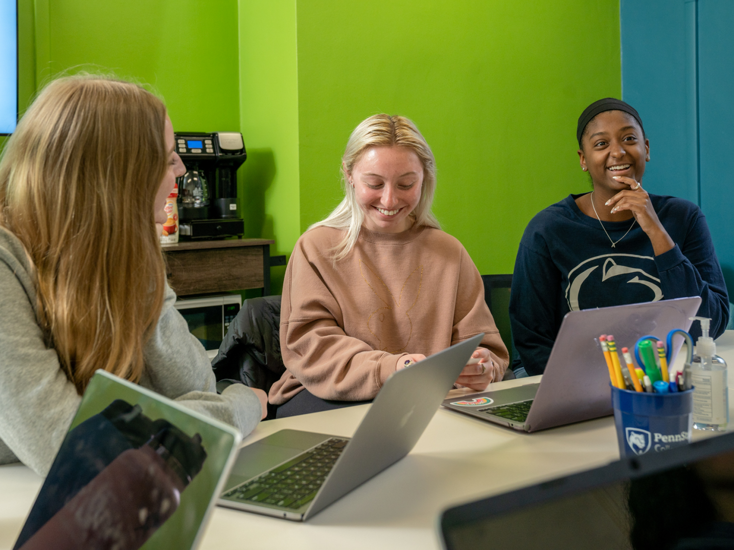 Riley Lingle, Abby Fusaro and Aliana Roman sit at a table behind laptops in the Chaiken Center for Student Success.