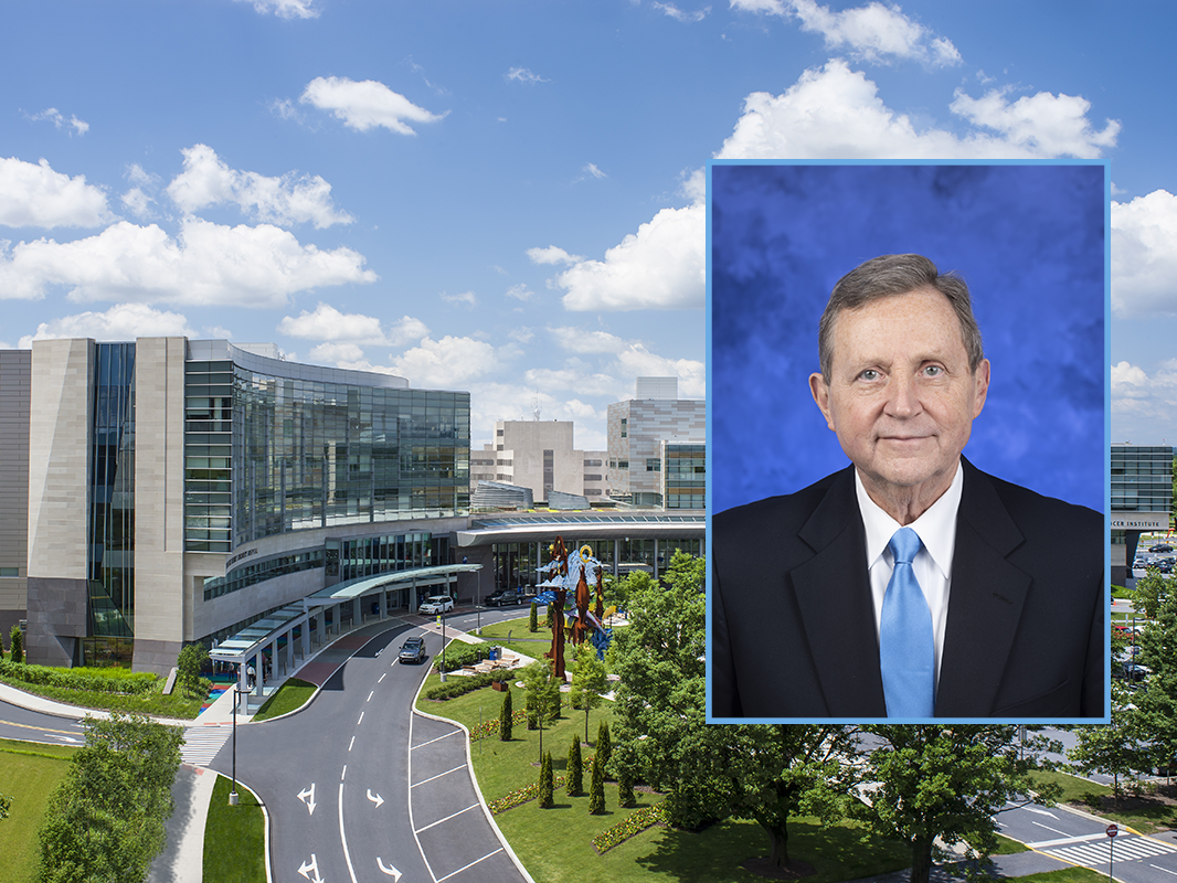Portrait of Robert Harbaugh wearing a business suit. The portrait is overlaid on a photo of Milton S. Hershey Medical Center.