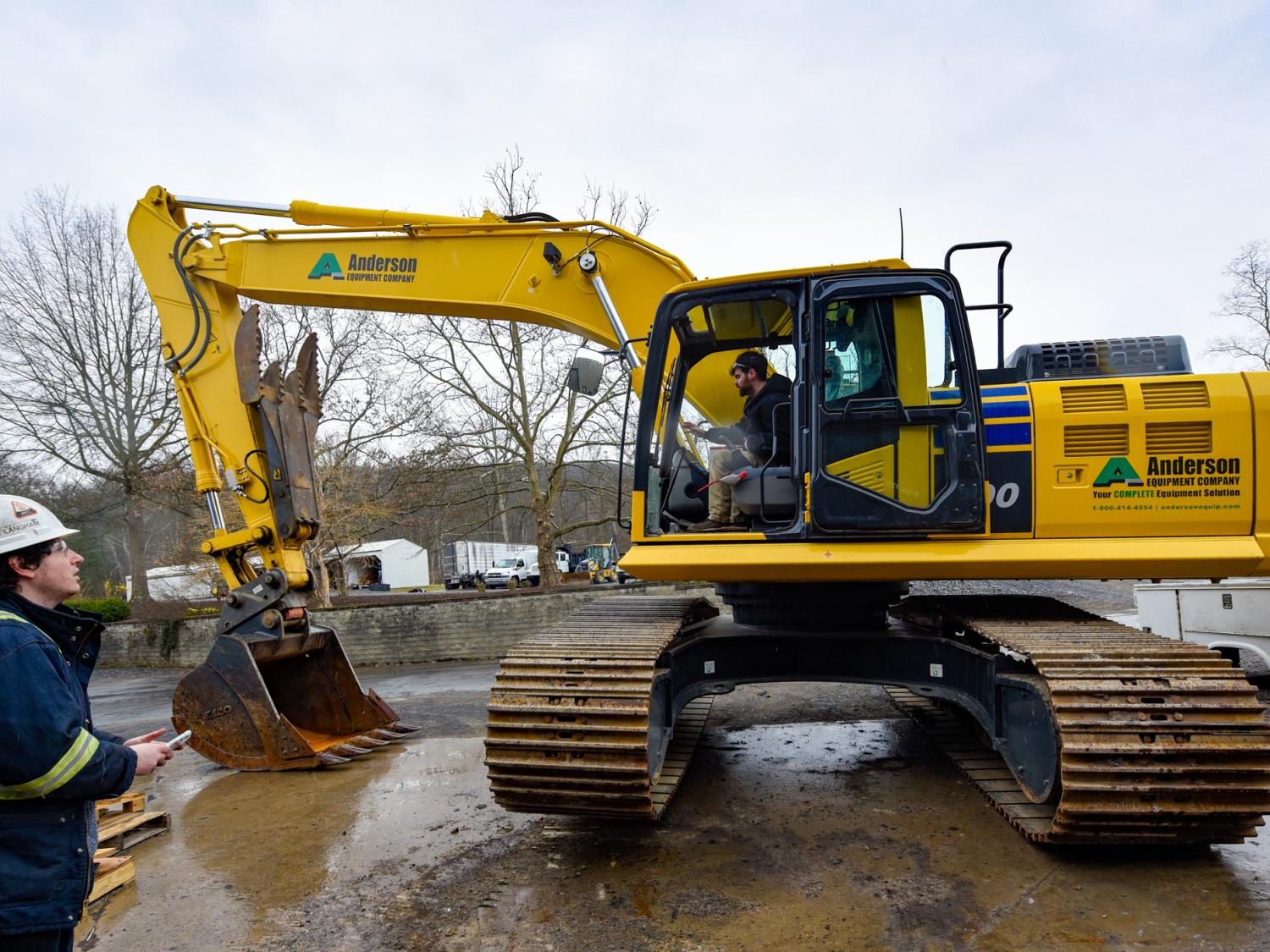 A man in a hard hat operating a large yellow exavacting machine