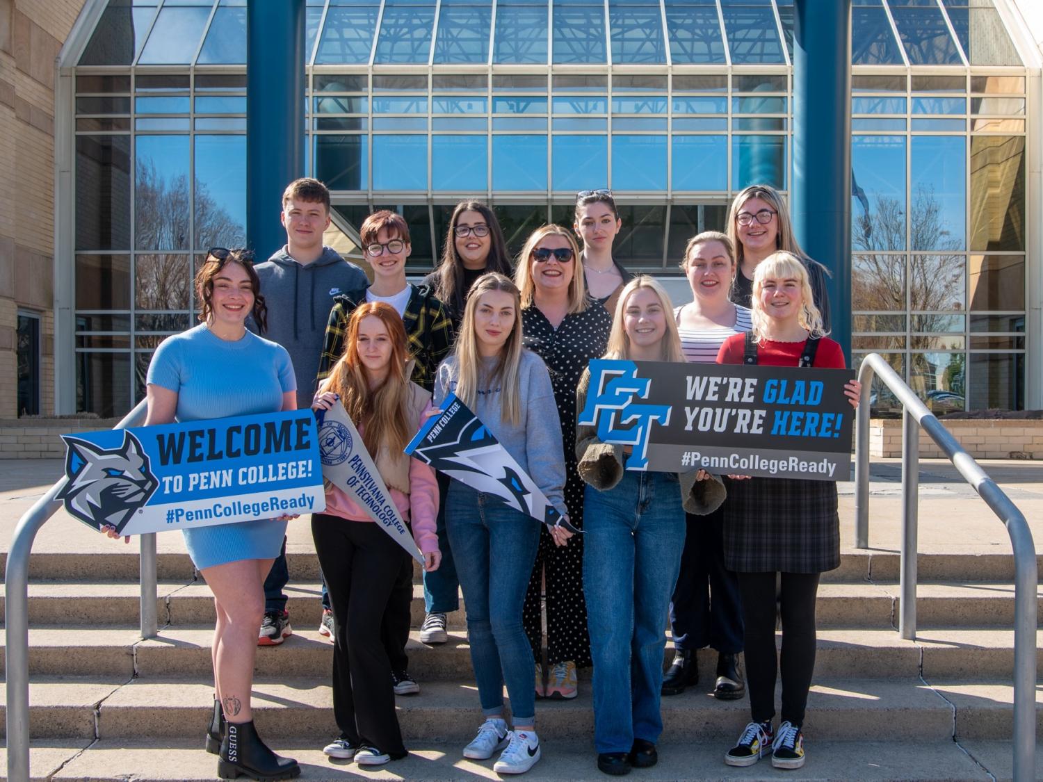 Students stand on steps at Penn College holding signs