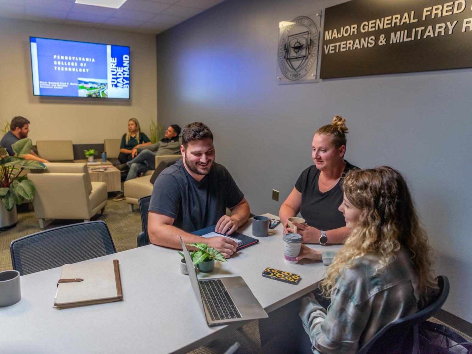 Three people sit at a table and talk.
