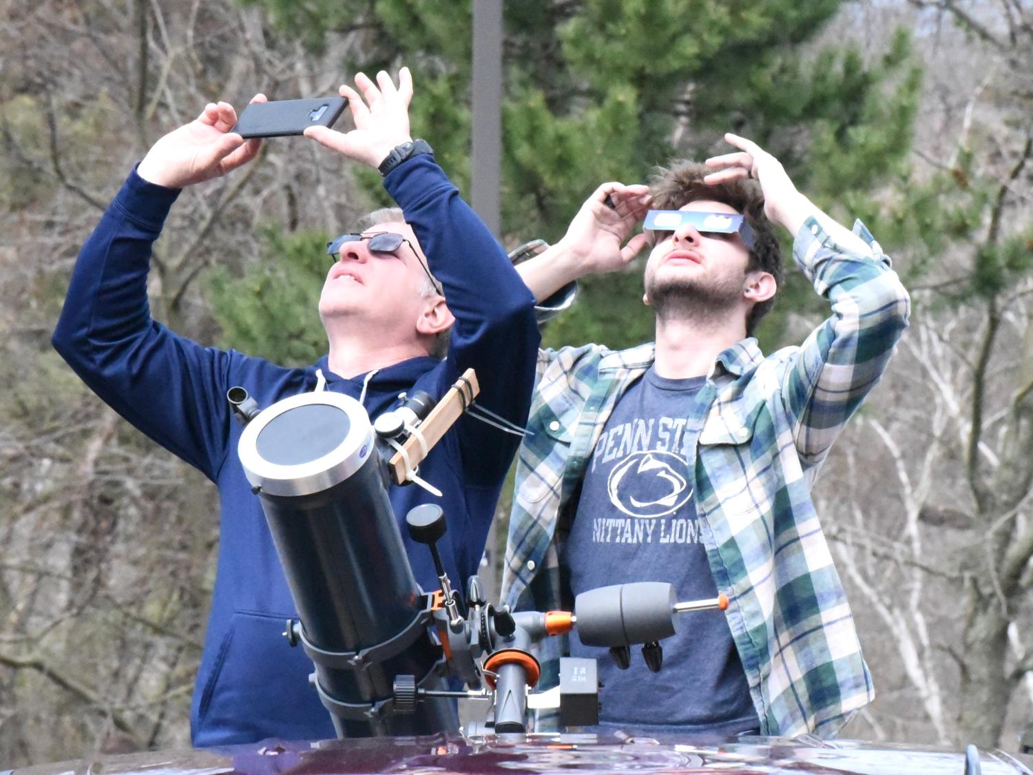 Two people with telescopes looking up at eclipse