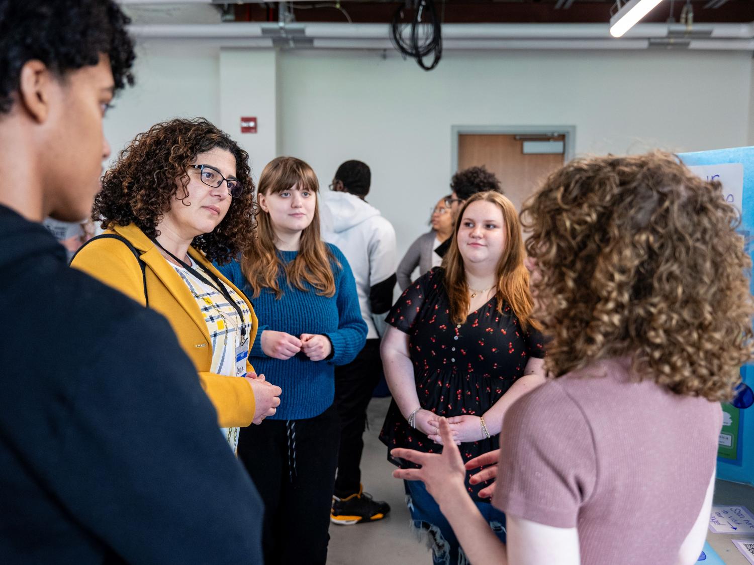 A group of people talking about a poster project at a symposium.