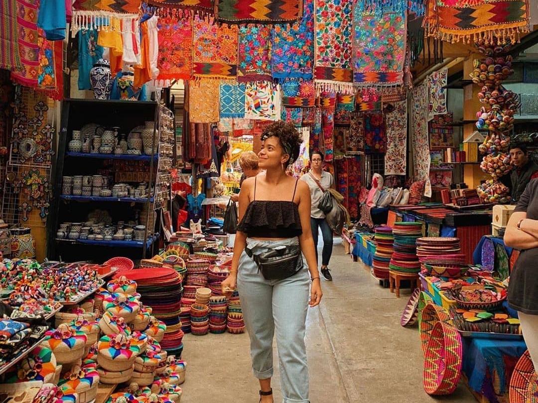 Woman walking among colorful tapestries in a street market