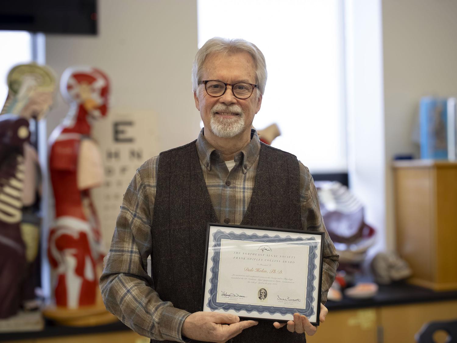 Professor Dale Holen shows off his award certificate that he recently received from the Northeast Algal Society