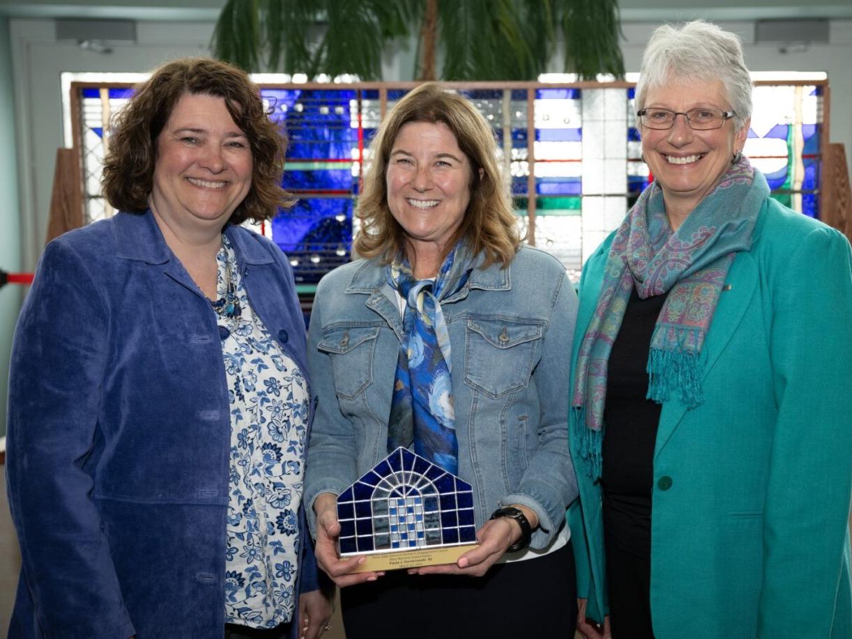 Women's Engagement Council board members Melanie Ford and Priscilla Hamilton present the Mary Behrend Impact Award to Paula J. Dombrowski.