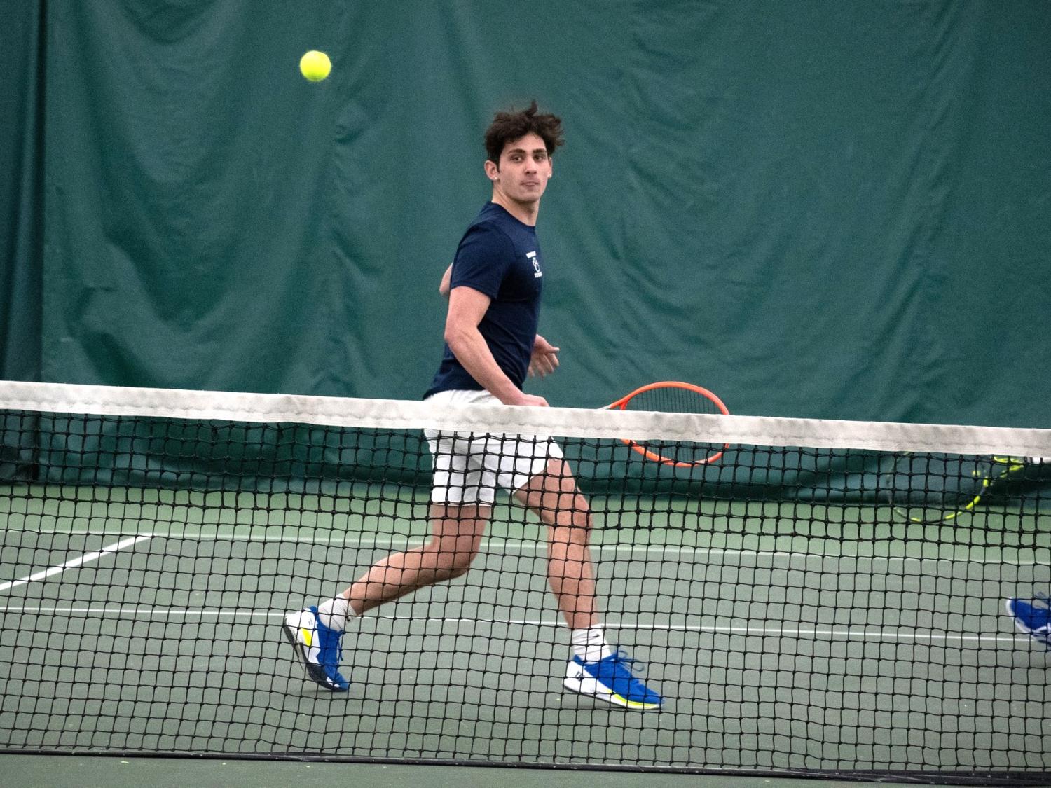 A member of the Penn State Behrend tennis team hits a backhand shot.