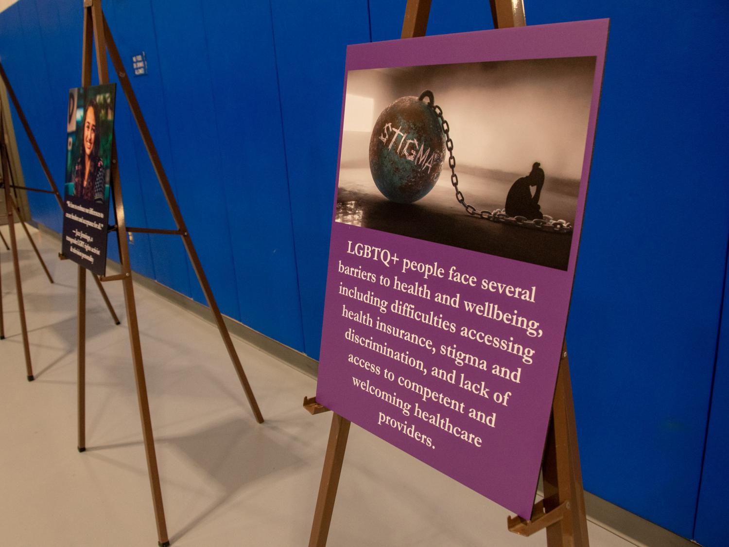 A poster on a stand shares barriers that LGBTQ+ individuals may face when accessing health care