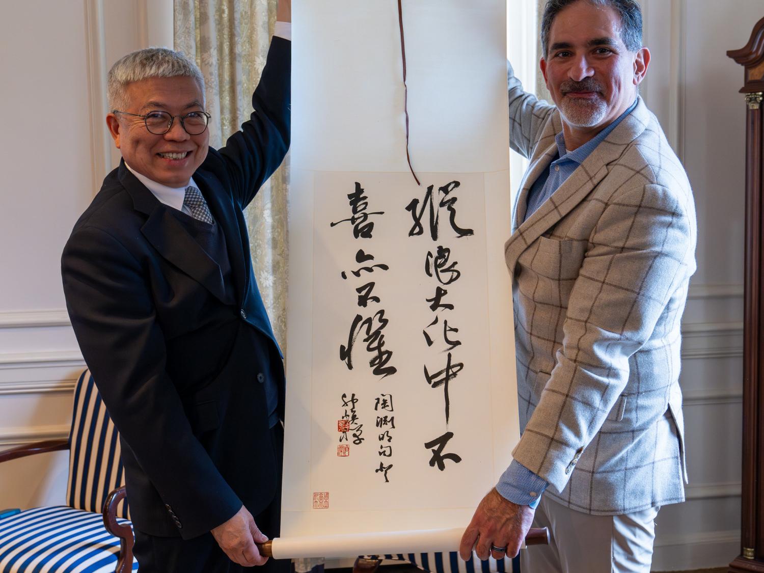 Two men holding a scroll of Chinese calligraphy