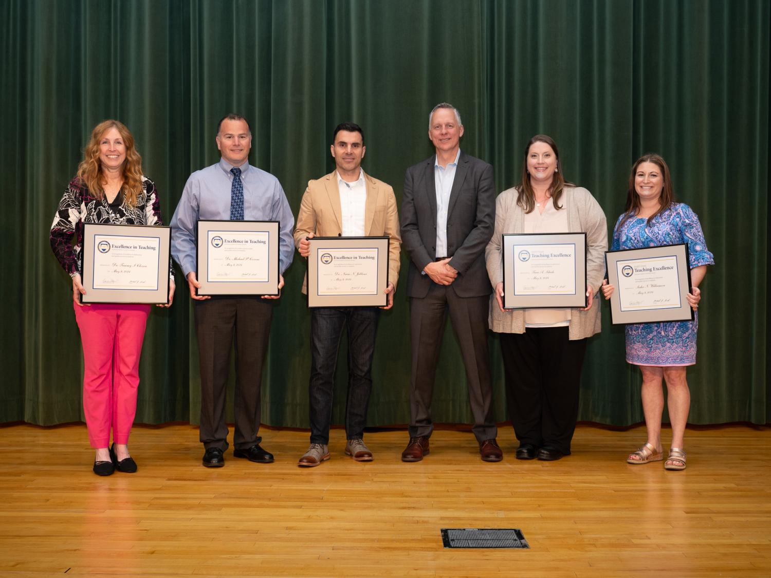 A group of people on a stage holding awards