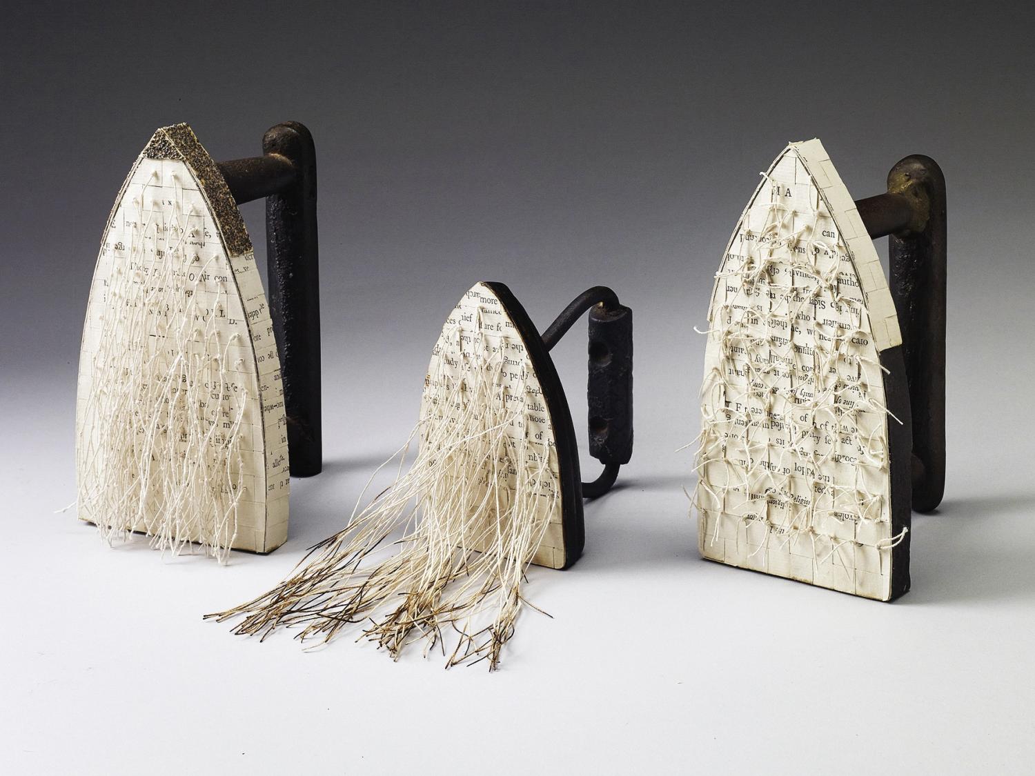 Three antique irons covered in paper, as depicted by artist Carole Kunstadt.