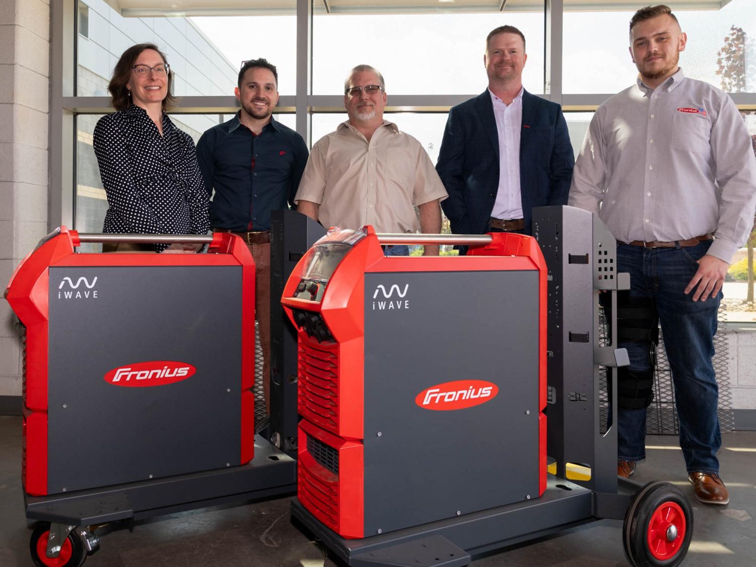 Five people standing behind two I-Wave 300 machines.
