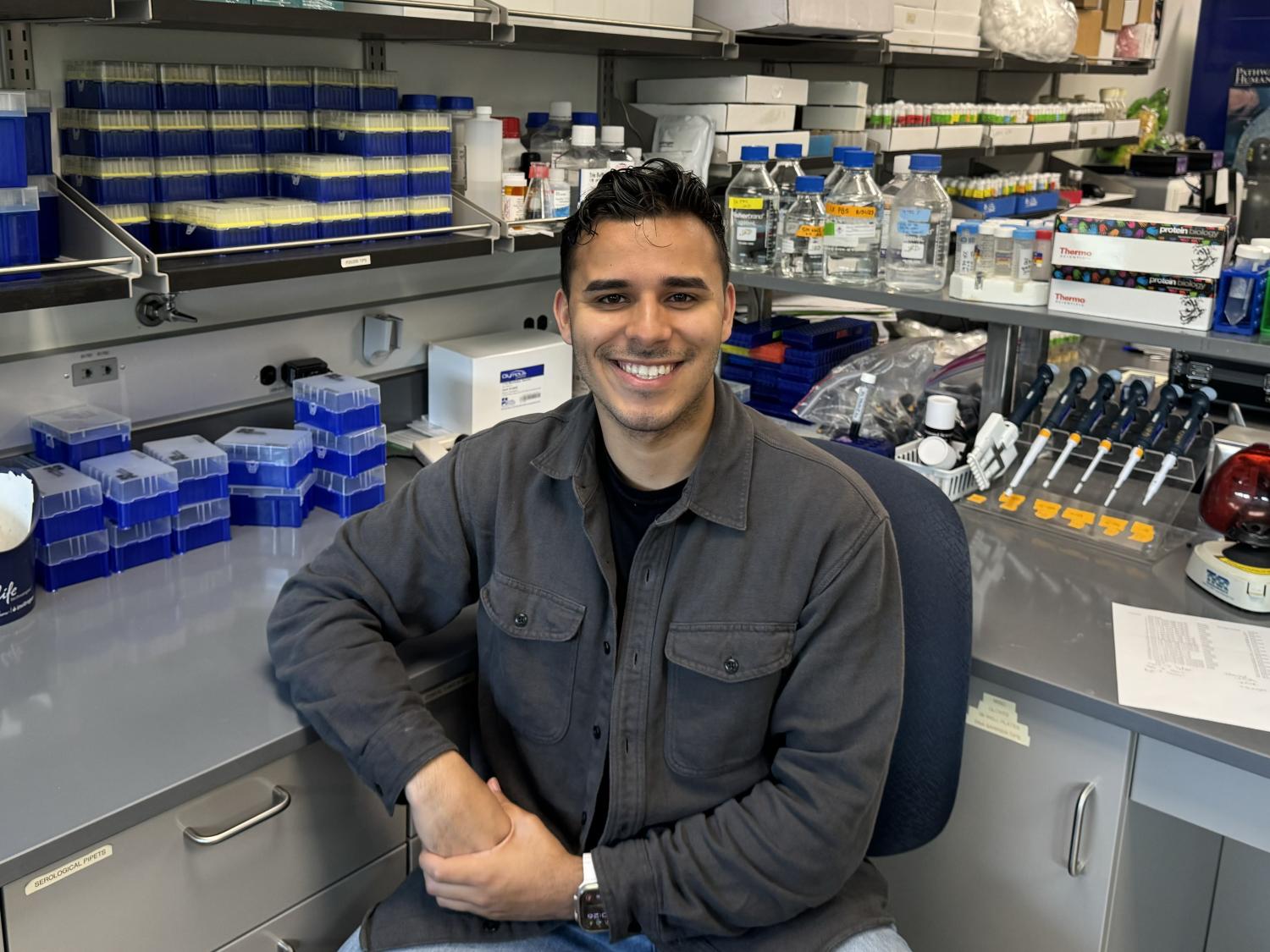 Erick Astacio surrounded by laboratory equipment