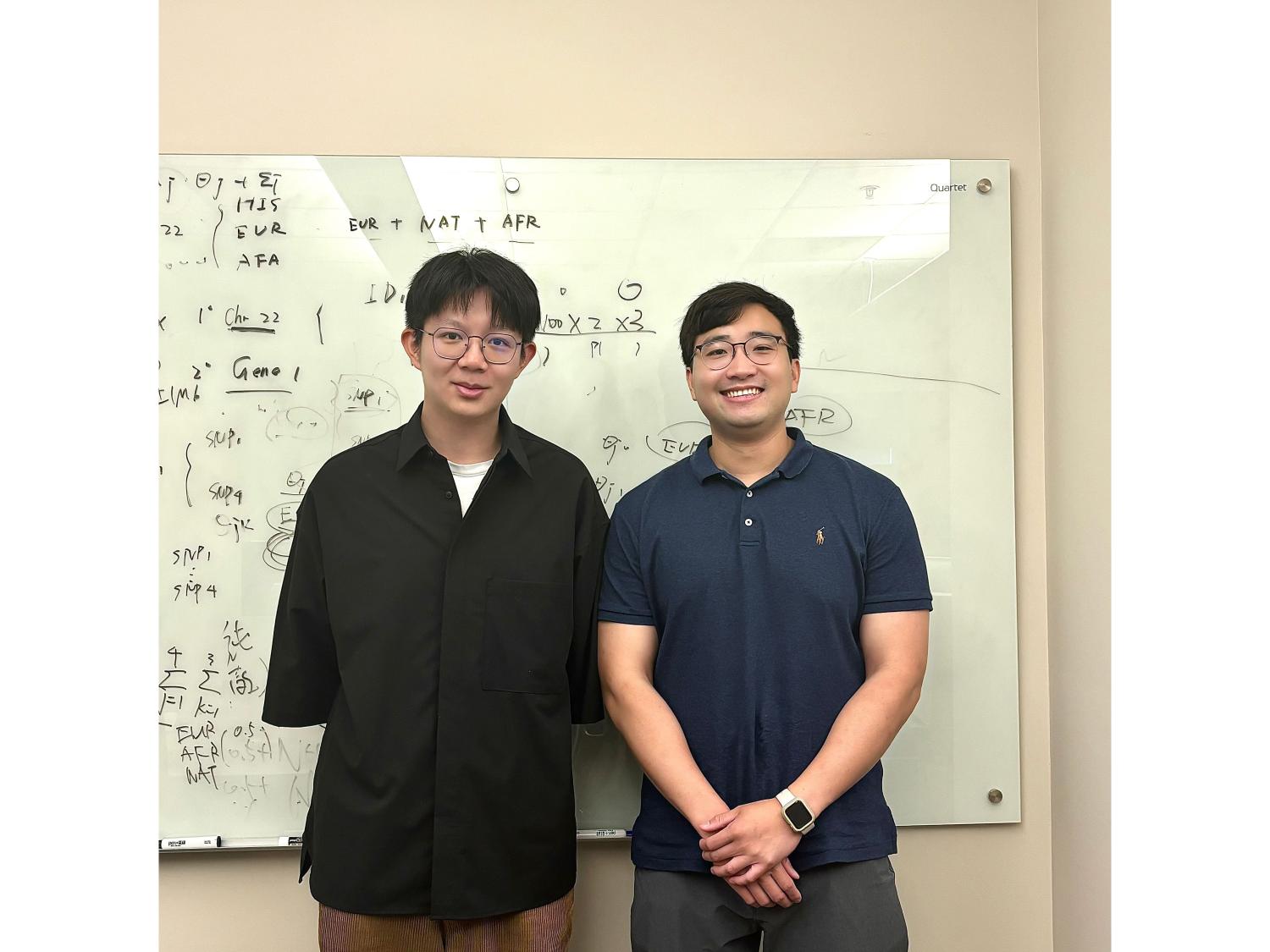Two people standing in front of a white board