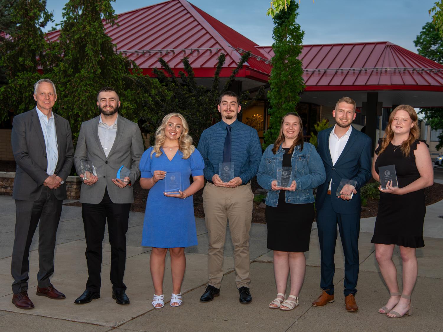A row of people standing holding awards