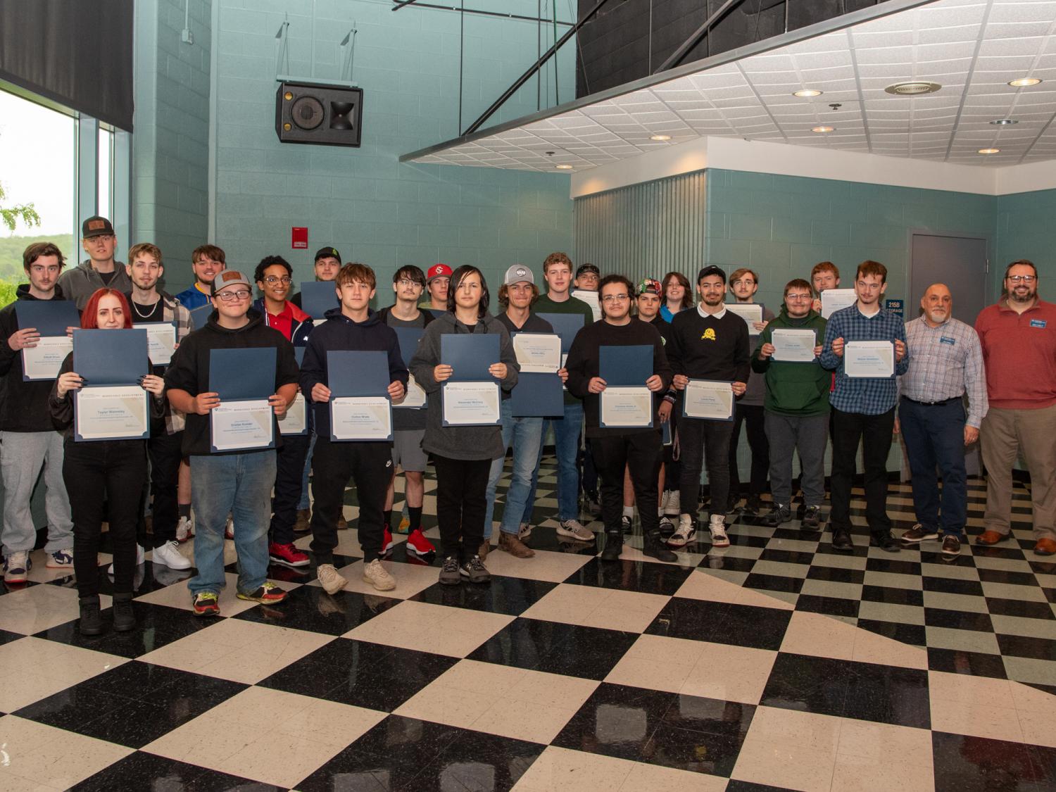 A large group of happy students holding up workshop completion certificates