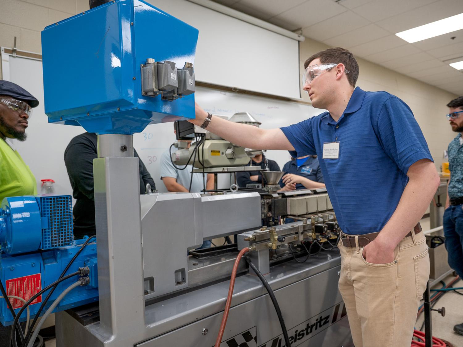 Industry professionals work with a Leistritz twin screw extruder in an extrusion lab at Penn College.