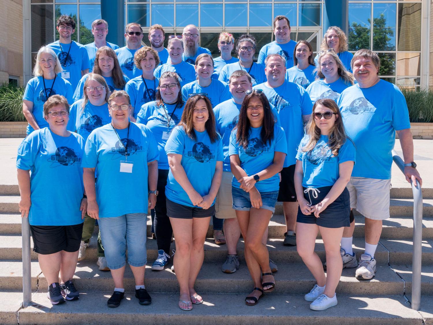 A group of people wearing bright blue shirts pose for a photo