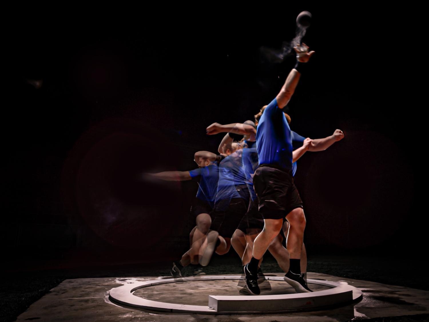 A person performs an Olympic shot put throw with a black background.