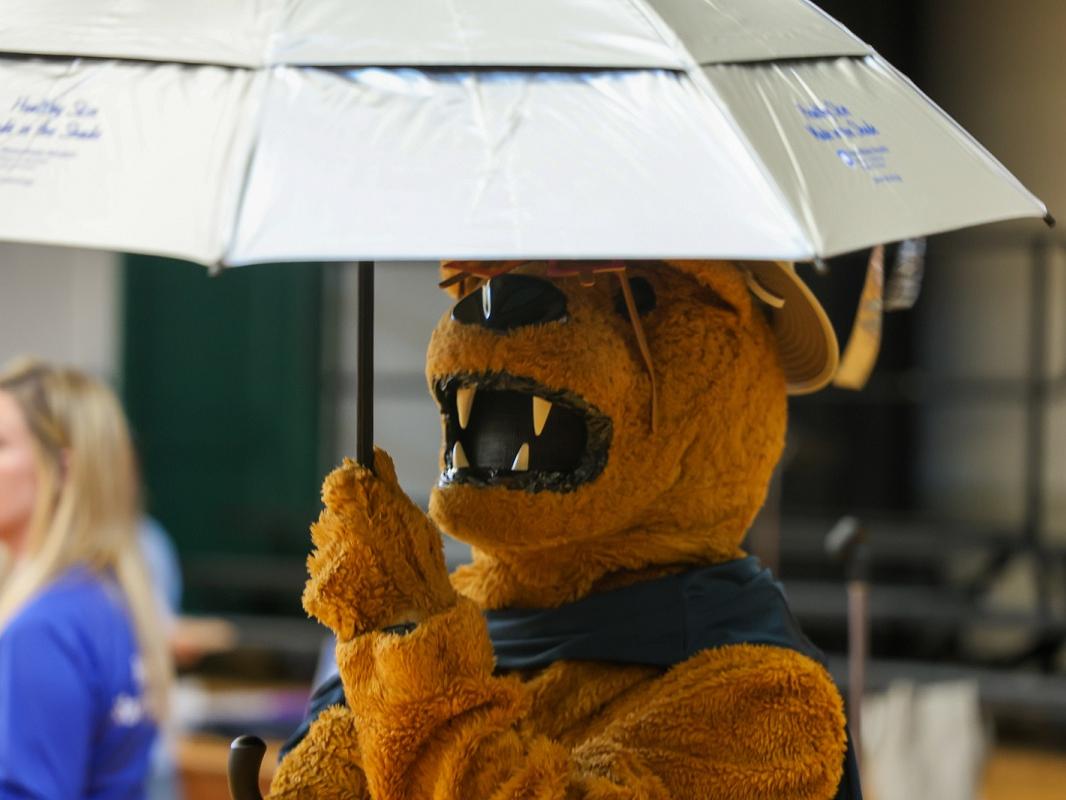 The costumed Penn State Nittany Lion raises an umbrella.