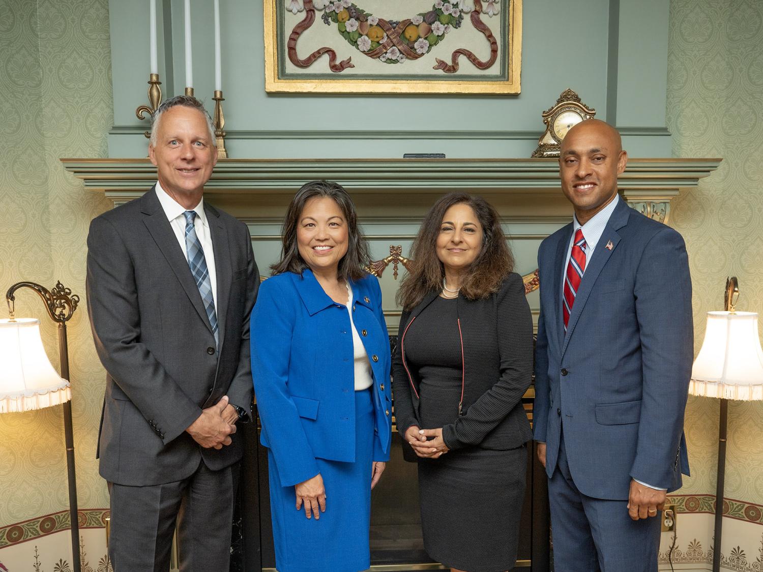 Four people pose for a photo in a parlor