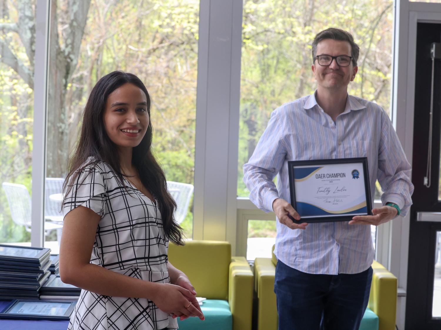 Two people stand with a framed certificate 