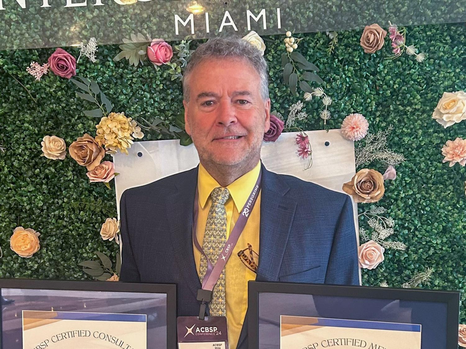 Chip D. Baumgardner holding two framed certificates