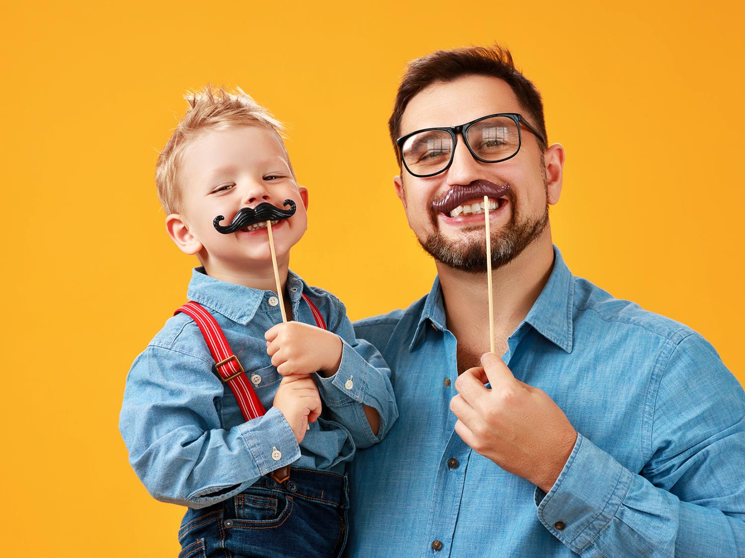 Adult and child with fake mustaches on a yellow background 