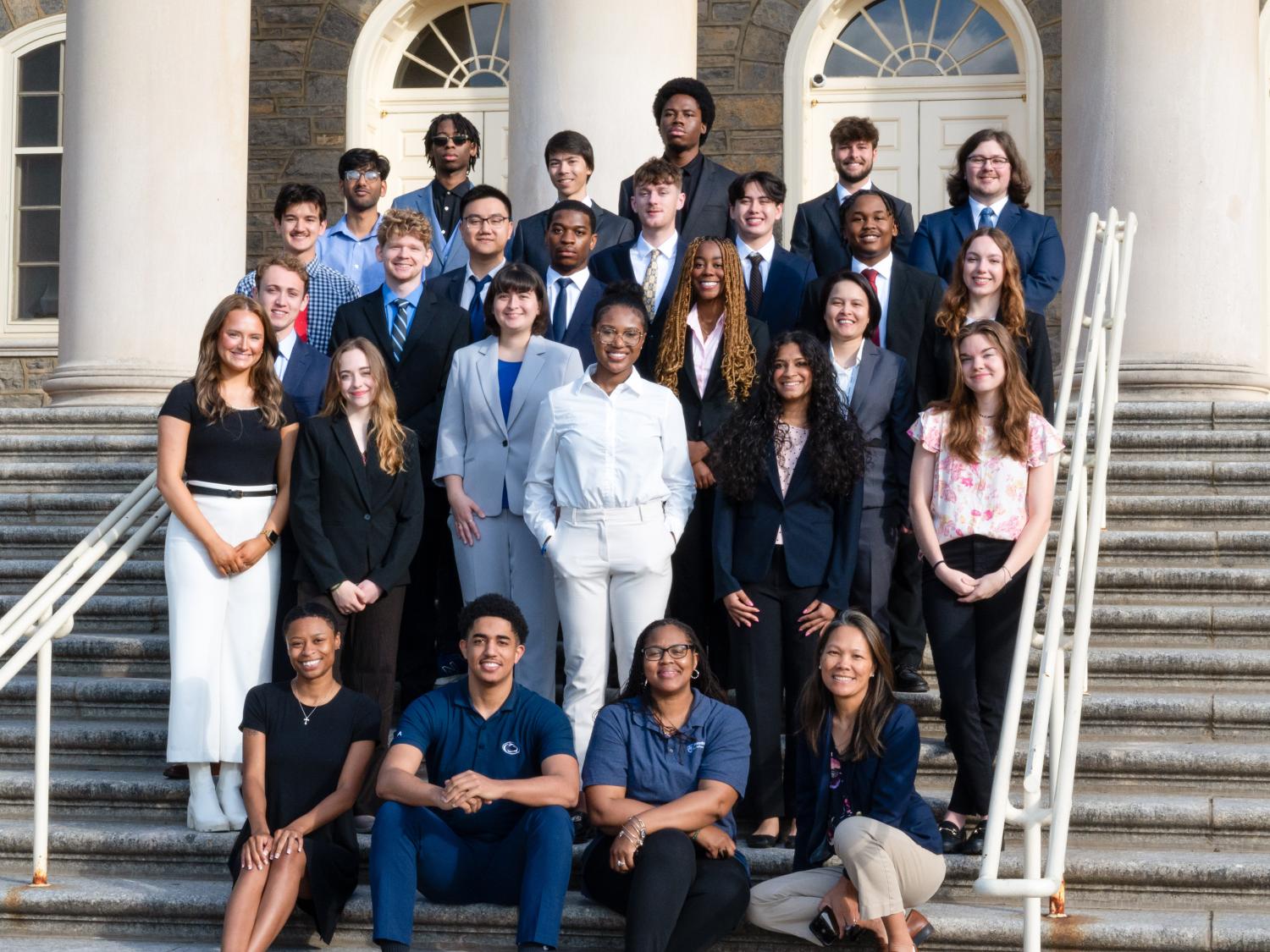 A group of 24 students pose on Penn State's Old Main steps