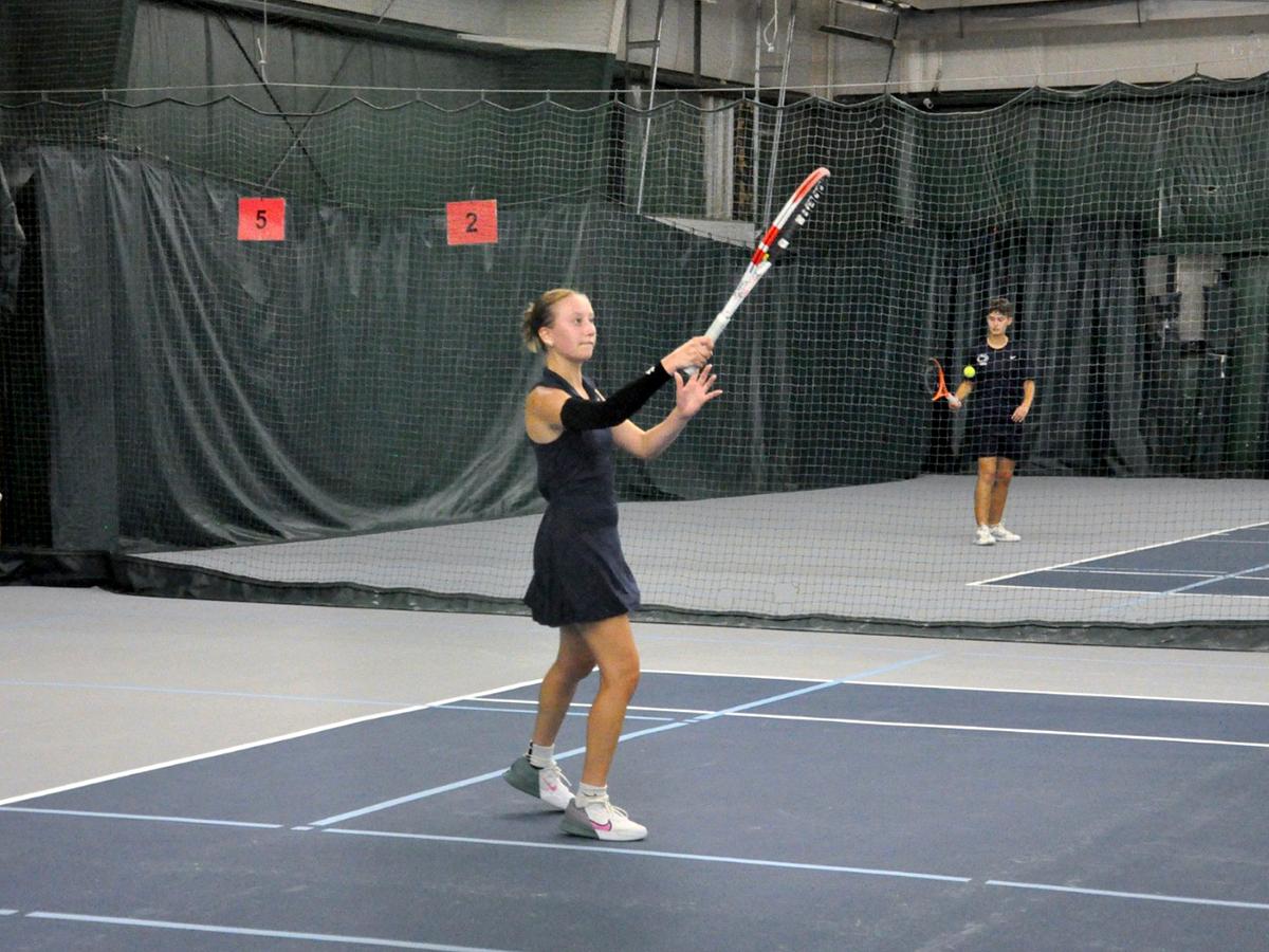 Penn State Altoona student-athlete Lexi Colaianni playing tennis in an indoor facility.