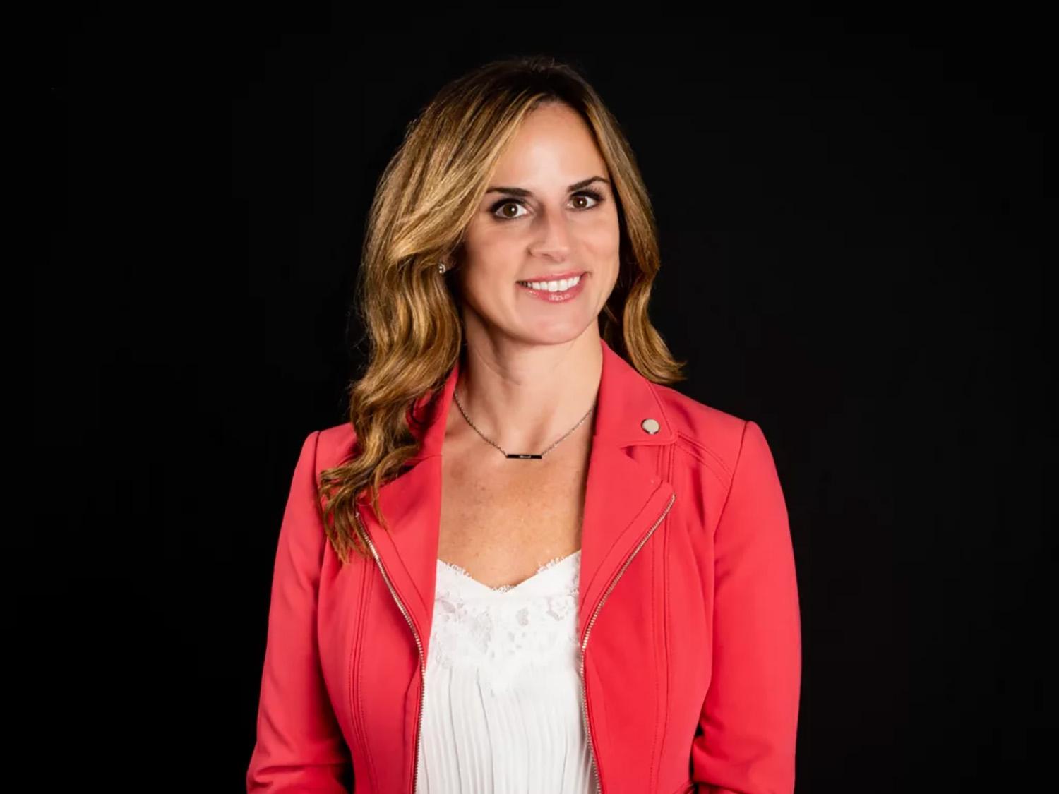 A photo of Dr. Zona wearing a red jacket in front of a black background