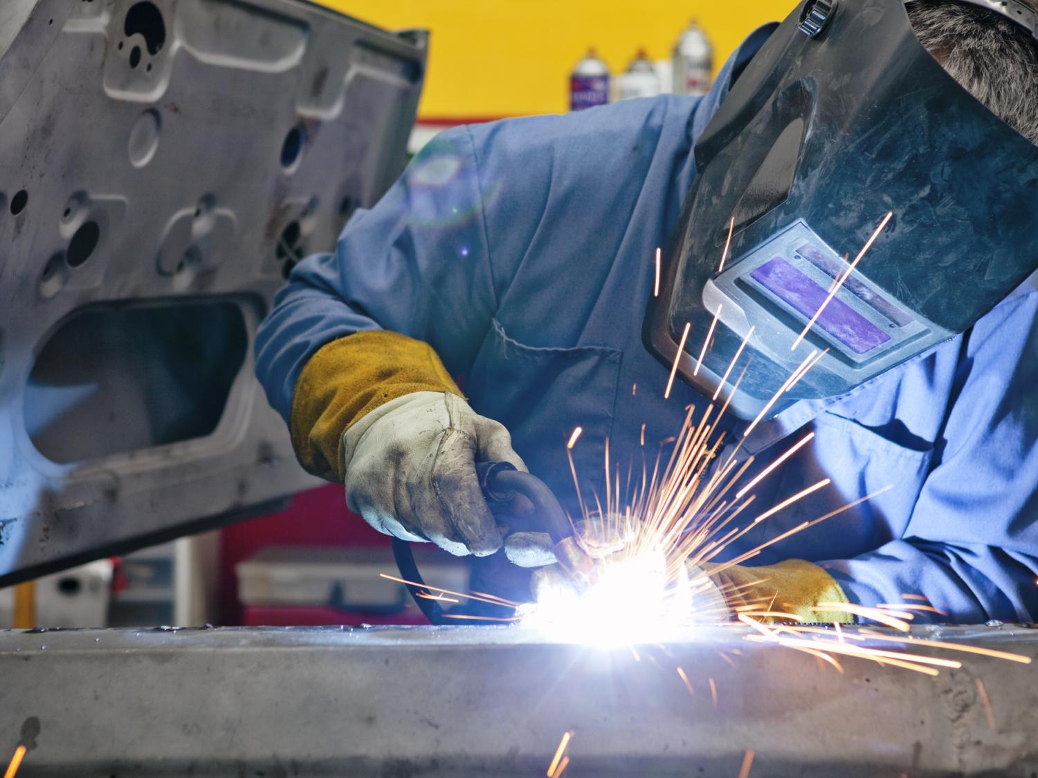 A welder uses a torch on a car