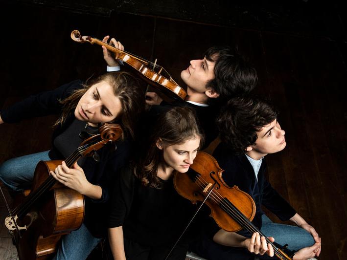 Four white musicians hold their string instruments in a bird's-eye view photo.
