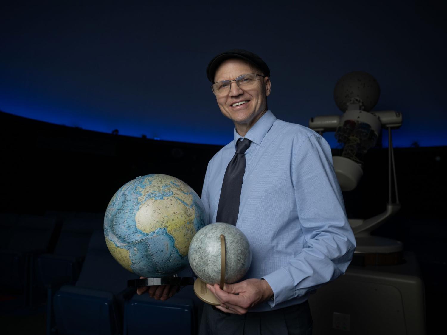 Darren Williams, an astronomer at Penn State Behrend, holds models of the Earth and the moon.