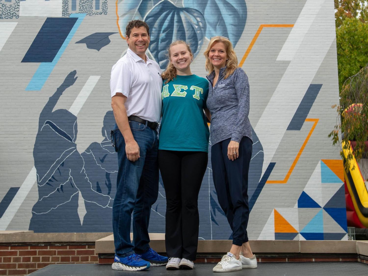A student poses with her parents at Penn State Behrend's Parents, Families and Alumni Weekend.