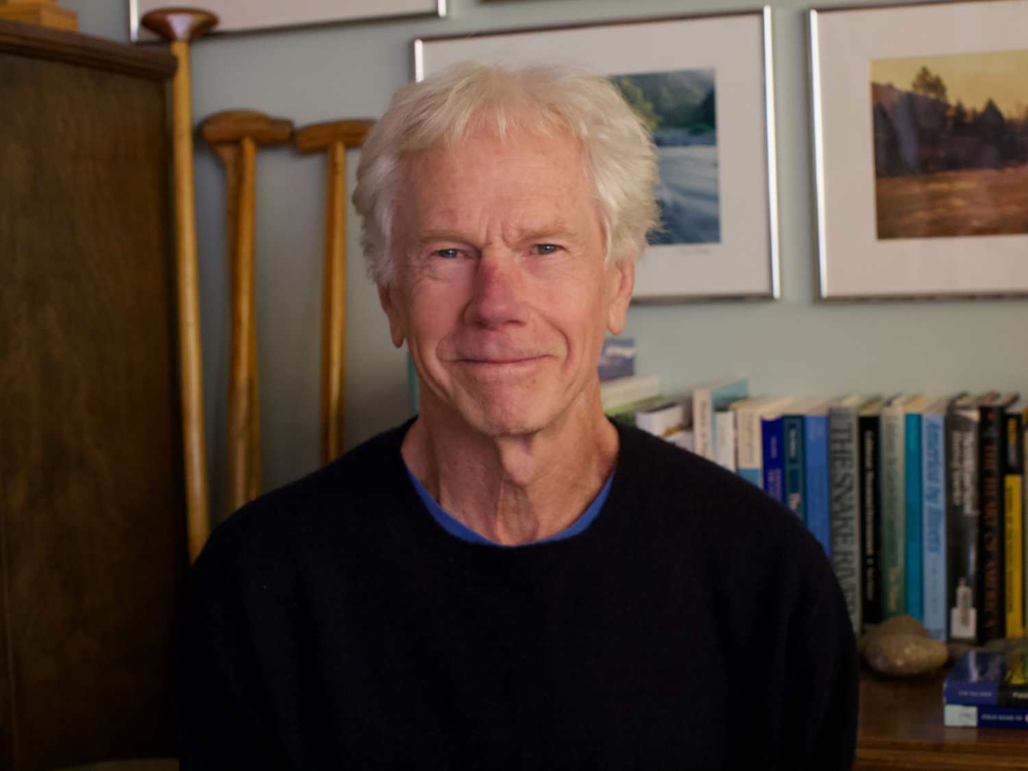 A man smiling in front of a bookshelf.